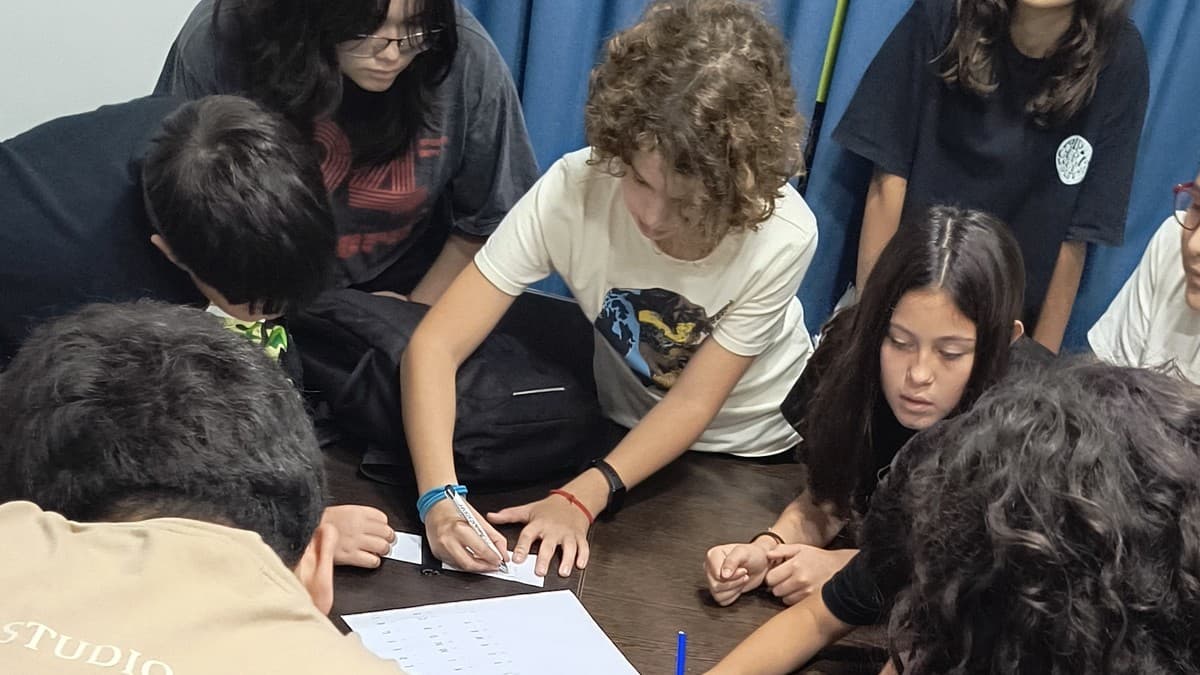 Grupo de alumnos básicos conversando en inglés en ronda, guiados por la docente